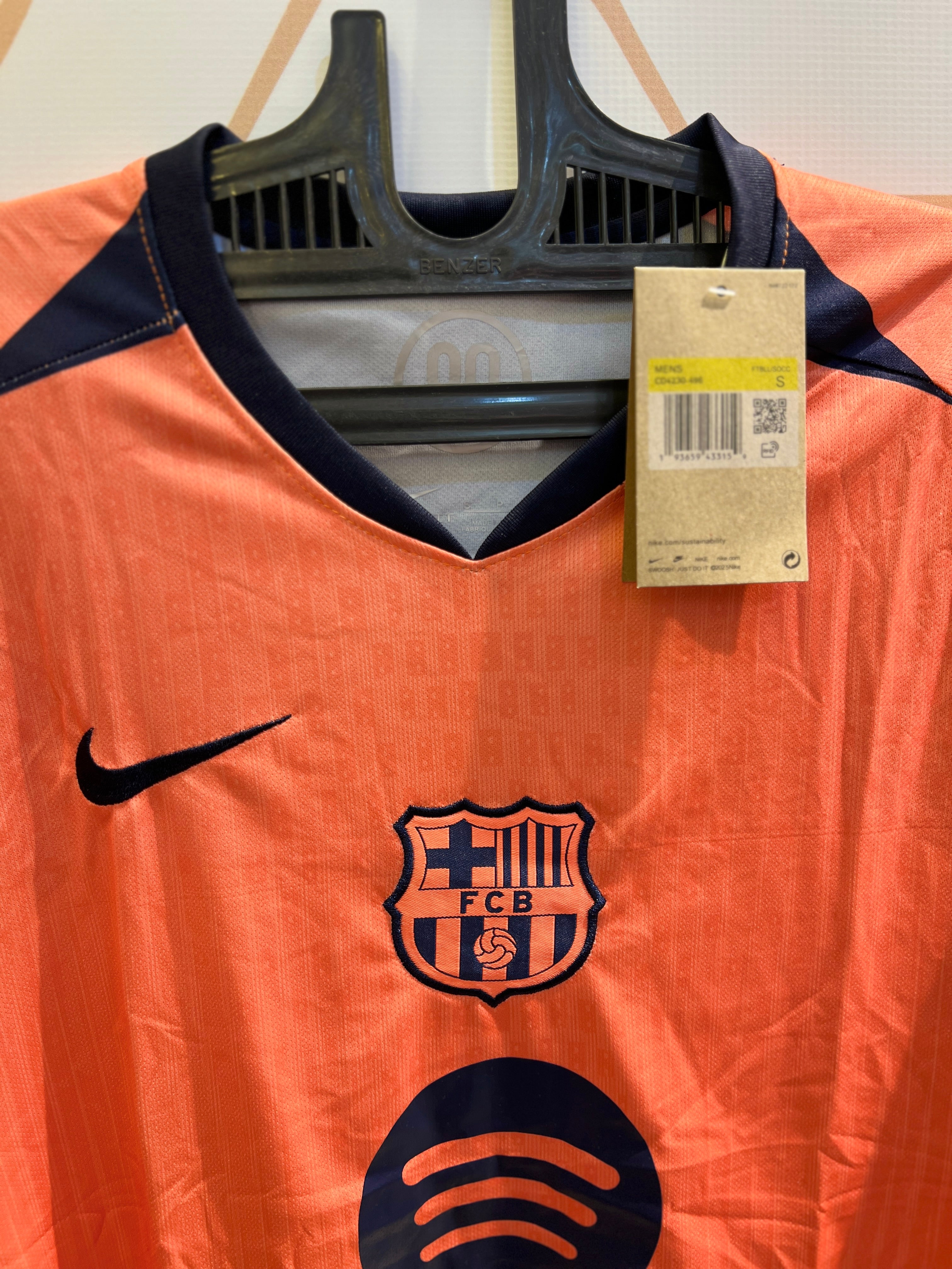 Close-up of Barcelona Away Orange 25/26 Kit fabric design and FCB crest