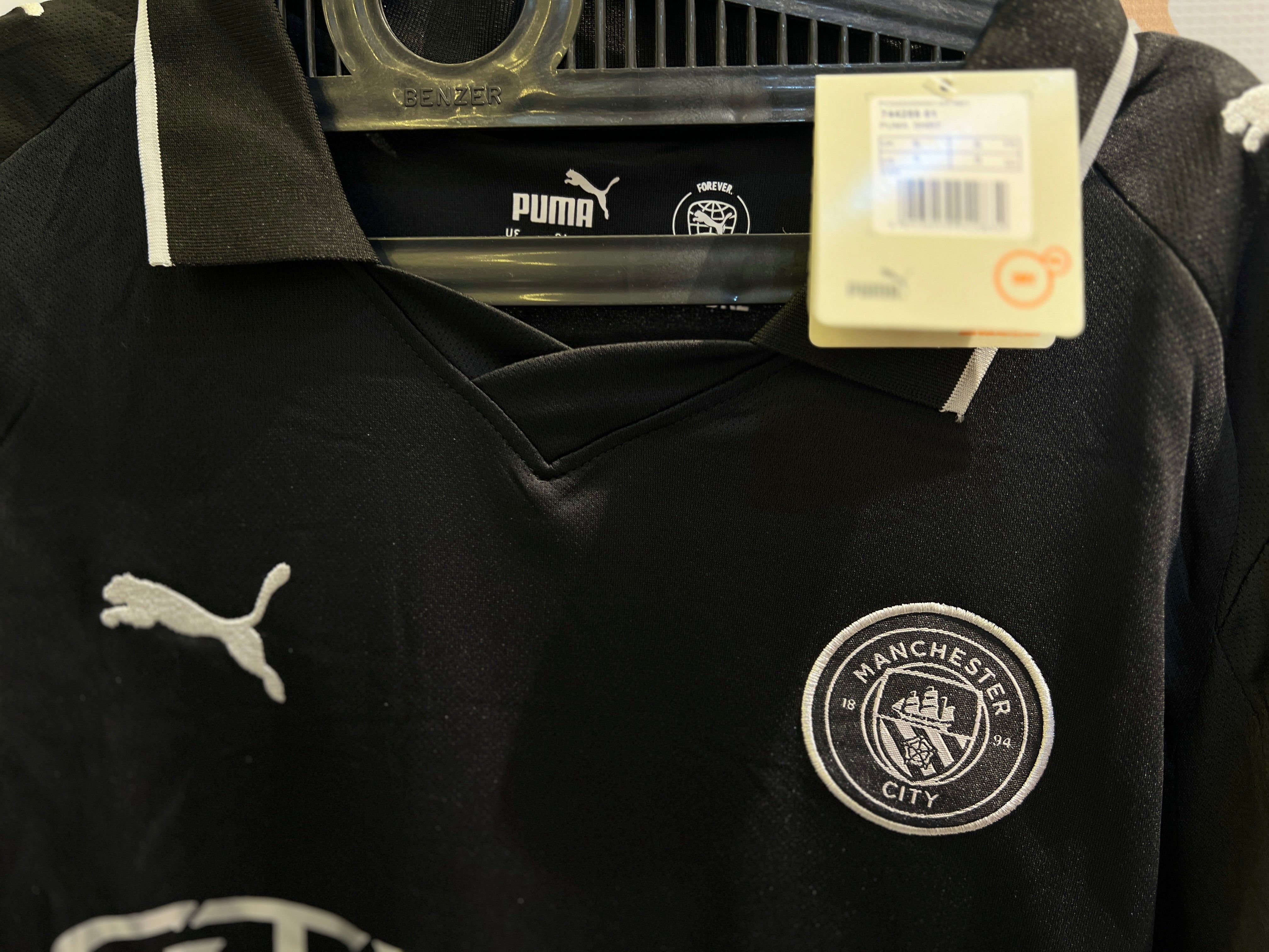 Close-up of Man City 25/26 Away Black Kit fabric design and crest detail